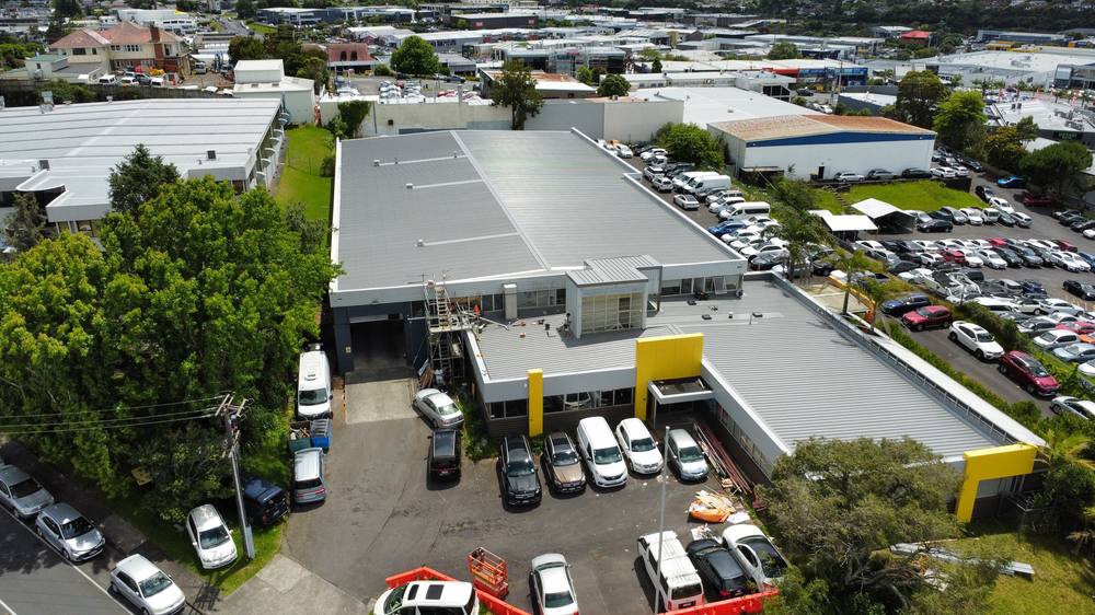 Aerial view of a large commercial building in an Auckland industrial area with a newly laid grey longrun roof